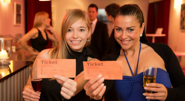 Photo of two women smiling and holding tickets